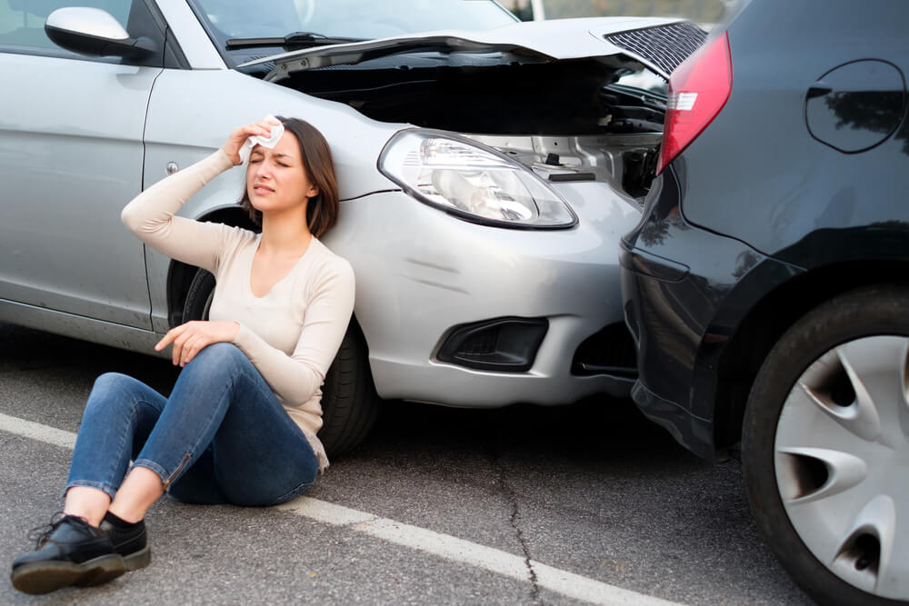 Injured woman driver suffering whiplash from car collision.