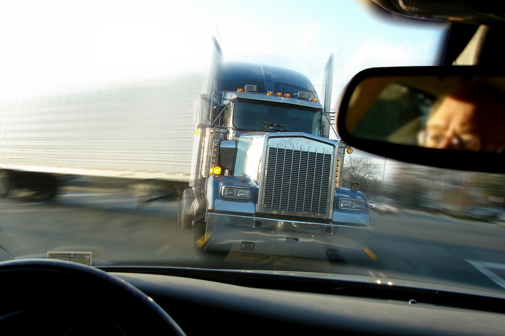 Close call imminent crash accident with truck viewed from inside a passenger car in rear view mirror.