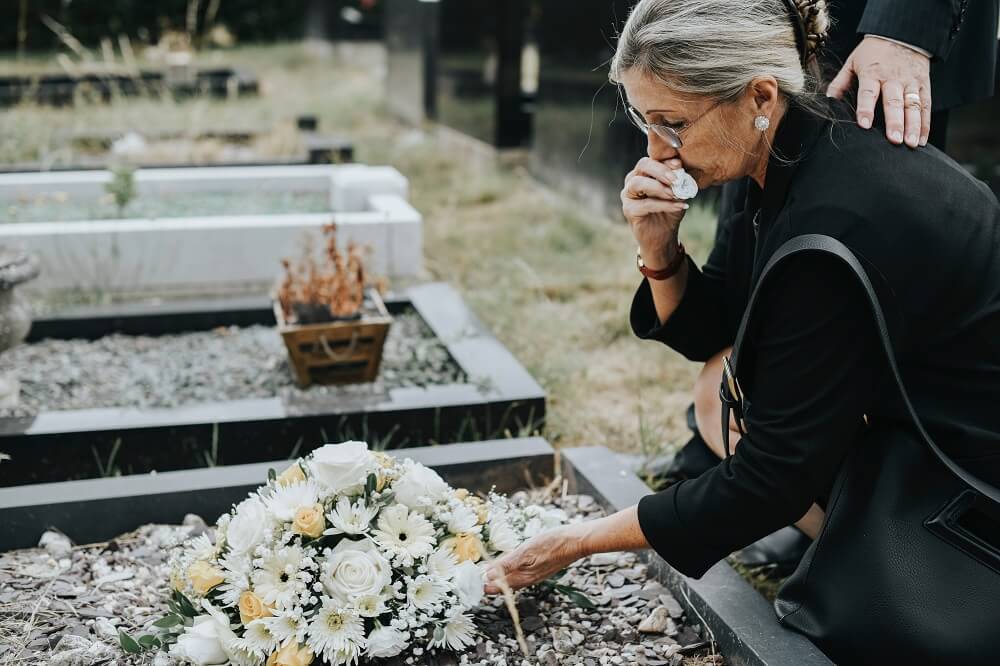 Sad mother crying in the grave of her late son.