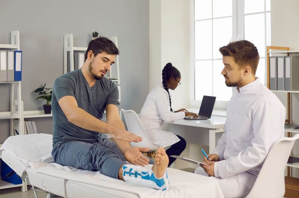 Doctor checking his patient's leg injuries at work.