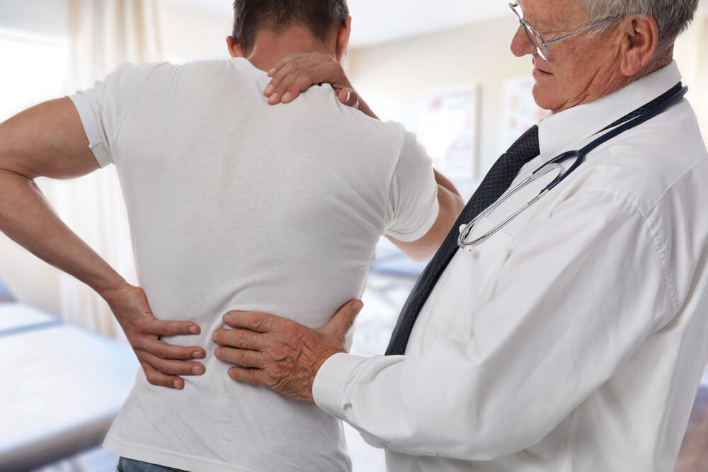 Doctor checking patients back pain from slip and fall accident.