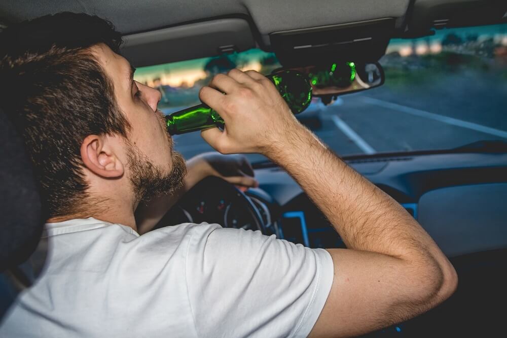Drunk driver drinking liquor while driving.