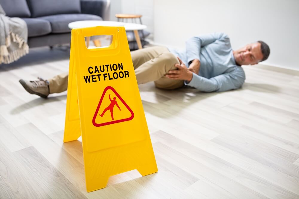Man slip and fall from wet floor near caution sign.