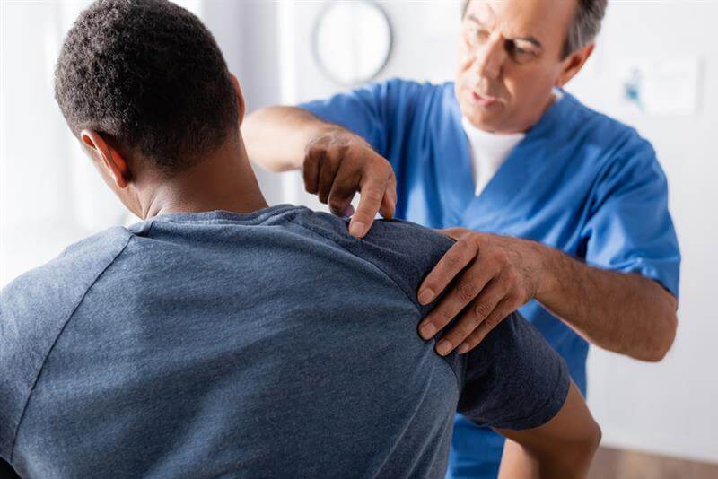 Chiropractor checking the shoulder injury from the car accident of his patient.