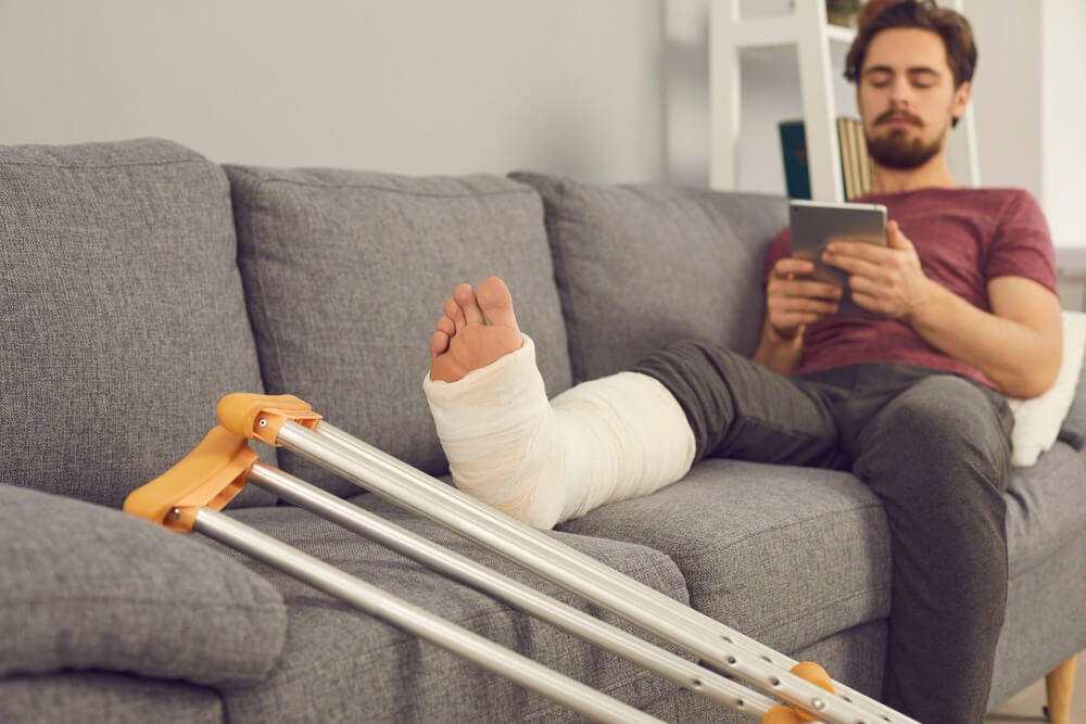 Man with leg injury due to car accident using his mobile phone.